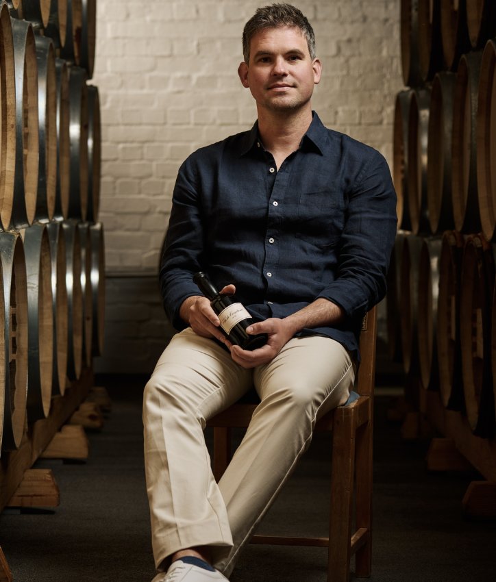 Le maître de chai Matthew Day avec une bouteille de Vin de Constance dans le chai à barriques